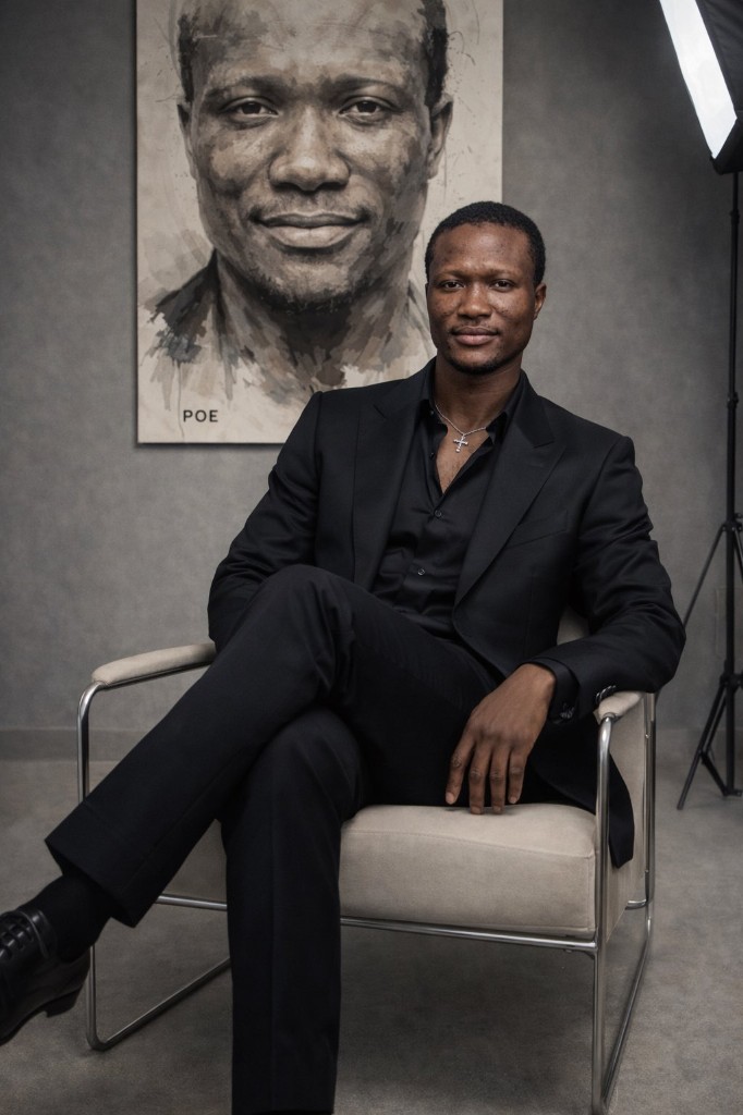 Poe seated in front of a studio portrait